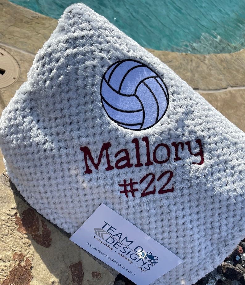 May include: A white, fuzzy blanket with a white volleyball and the name "Mallory #22" embroidered in maroon.