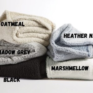 May include: Five folded blankets in different colors: oatmeal, shadow grey, black, heather navy, and marshmallow.