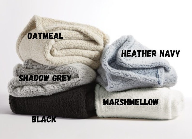 May include: Five folded blankets in different colors: oatmeal, shadow grey, black, heather navy, and marshmallow.