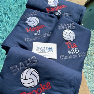 May include: Four navy blue fleece blankets with embroidered volleyball designs. Each blanket features a volleyball, a name, a number, and the text "BAHS" and "Class of 2024".