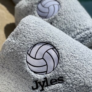May include: A gray, fuzzy towel with a white volleyball and the name "Jyles" embroidered in black.