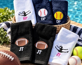 May include: A collection of six folded towels in white, navy blue, and black, featuring embroidered sports motifs including a cheerleader, a baseball, a softball, and a football. Each towel is personalized with embroidered initials BP, DP, or JT.