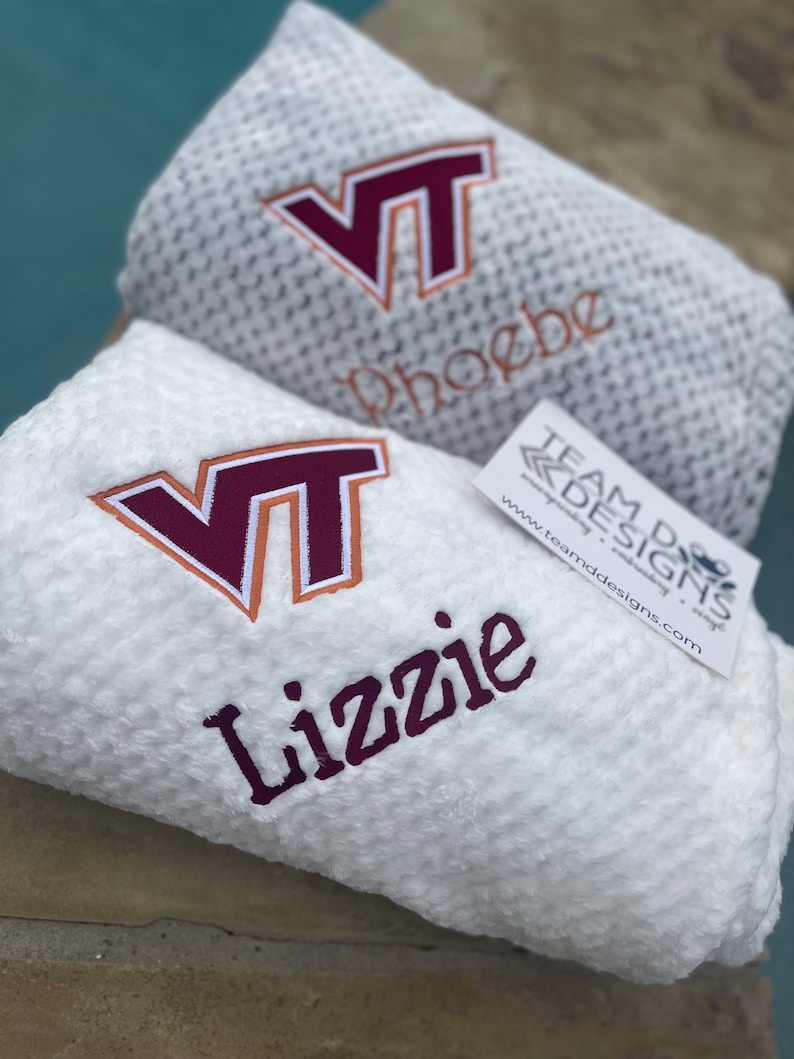 May include: Two white fleece blankets with embroidered VT logos and personalized names. The top blanket says "phoebe" and the bottom blanket says "Lizzie".