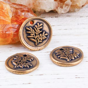 May include: Three antique gold-toned metal charms with a raised design of a leafy branch. The charms have a hole at the top for attaching to jewelry or other crafts.