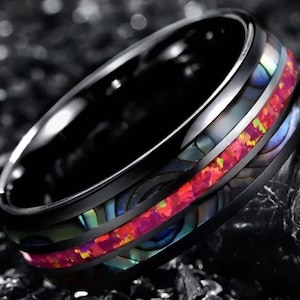 Può includere: Un anello in carburo di tungsteno nero con un'incisione di opale rosso e blu e un'incisione di madreperla nera.