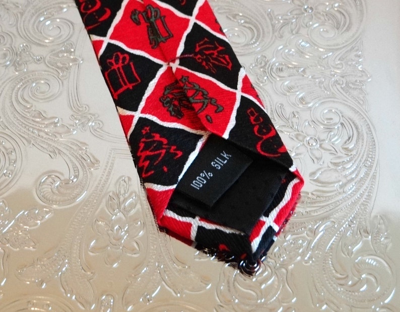 May include: A red and black silk tie with a diamond pattern and a white tag that says "100% Silk".