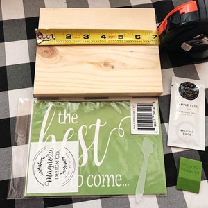 May include: A wooden sign with the text "the best to come..." on a green background. The sign is packaged with a stencil, a spatula, and a small packet of white paint. The sign is 7 inches by 10 inches.