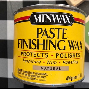 May include: A yellow can of Minwax Paste Finishing Wax. The can is labeled "Protects &bull; Polishes" and lists "Furniture &bull; Trim &bull; Paneling". The can is labeled "Natural" and has a warning label that reads "DANGER! FLAMMABLE SOLID! VAPOR HARMFUL. IRRITATES EYES, SKIN AND RESPIRATORY TRACT. Before using, carefully read CAUTIONS on back panel." The can is labeled "454 grams (1 LB)".