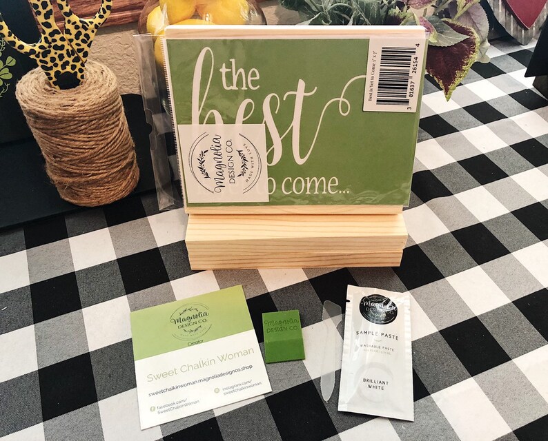 May include: A green wooden sign with the text "the best to come..." in white lettering. The sign is on a wooden stand and has a Magnolia Design Co. logo. There is a business card for Sweet Chalkin Woman and a sample of white chalk paste.