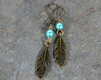 May include: A pair of bronze feather earrings with turquoise beads. The earrings are dangle style and have a simple wire hook fastening.