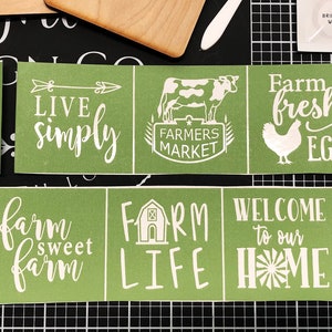 May include: Four green stencils with white vinyl lettering. The stencils feature farm-themed phrases like "Live Simply", "Farmers Market", "Farm Fresh Eggs", "Farm Sweet Farm", "Farm Life", and "Welcome to Our Home".
