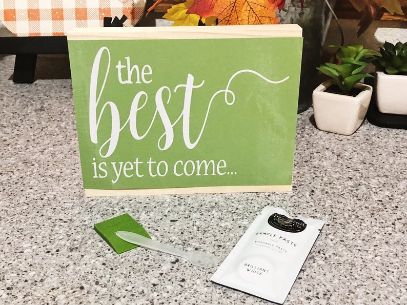 May include: A green wooden sign with white lettering that reads "the best is yet to come".