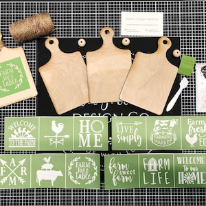 May include: A set of three unfinished wooden cutting boards with a farmhouse theme. The set includes stencils with various farm-themed phrases like "Farm to Table", "Welcome to the Farm", "Home", "Live Simply", "Farmers Market", "Farm Fresh Eggs", "Farm Sweet Farm", "Farm Life", and "Welcome to Our Home".