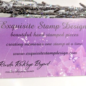 May include: A business card with a purple gradient background features the text "Exquisite Stamp Design." The card includes the phrases "beautiful hand stamped pieces" and "creating memories one stamp at a time."