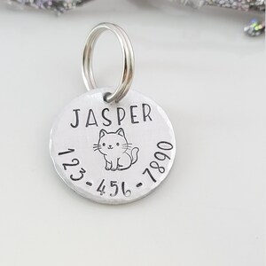 May include: Silver pet ID tag with a cat illustration and the name "Jasper" engraved on it. The tag also includes the phone number 123-456-7890.