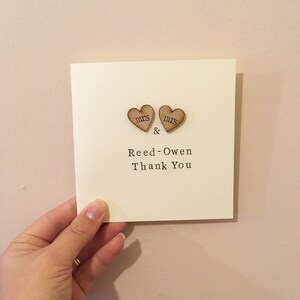 May include: A white card with two wooden hearts that say "mrs" and "mr" with the text "& Reed-Owen Thank You" printed on the card.