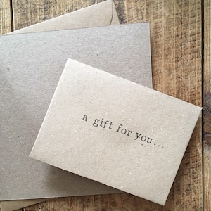 K&ouml;nnte beinhalten: Eine braune Karte mit dem Text "a gift for you..." darauf gedruckt.