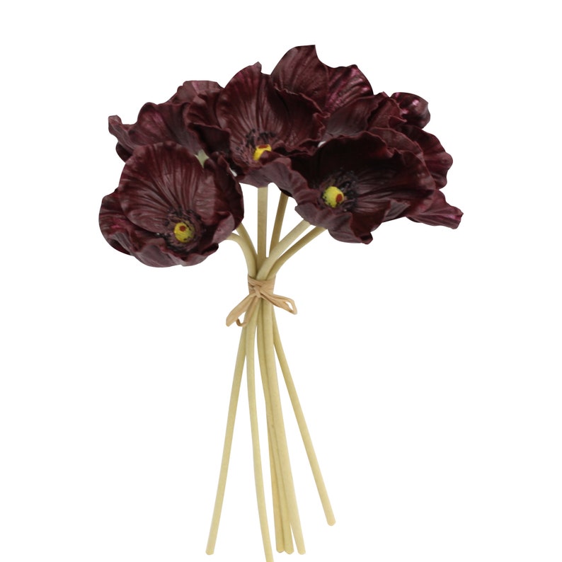 May include: A bouquet of 7 burgundy artificial poppy flowers with yellow centers. The stems are bundled together with twine and are a light beige color.