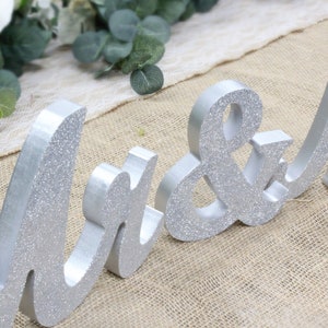 Peut inclure: Un panneau de mariage en bois avec inscription "Mr & Mrs" en lettres argent&eacute;es scintillantes.