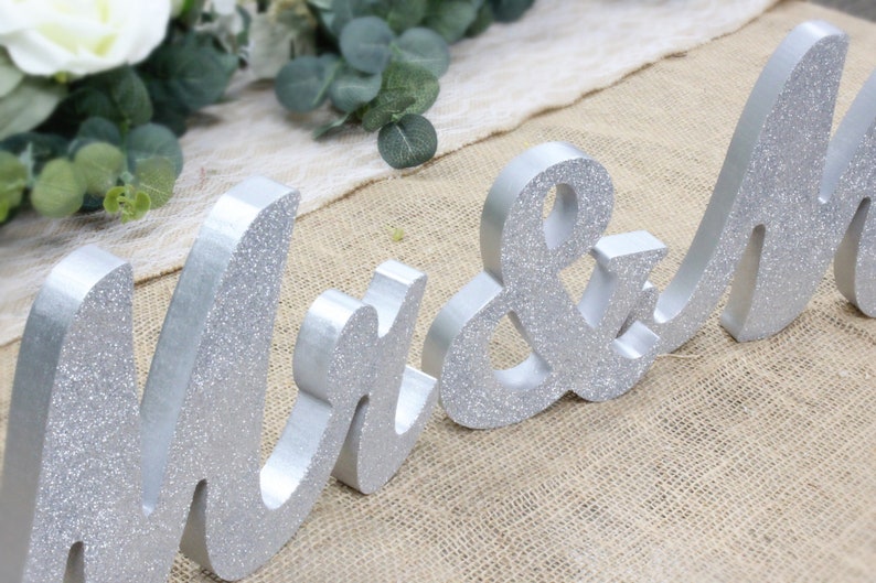 Peut inclure: Un panneau de mariage en bois avec inscription "Mr & Mrs" en lettres argent&eacute;es scintillantes.