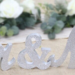 Peut inclure: D&eacute;cor de mariage en bois avec inscription "Mr. & Mrs." en paillettes argent&eacute;es.