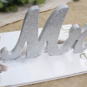 Peut inclure: Un panneau en bois avec des paillettes argent&eacute;es "Mr." pour un mariage ou un autre &eacute;v&eacute;nement sp&eacute;cial. Le panneau est en bois et a une police cursive.