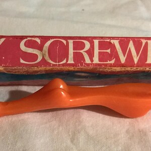 May include: An orange screwdriver with a cartoon face on the handle and the text "SEXY SCREWDRIVER" on the red and white box. The screwdriver has a unique, ergonomic design.