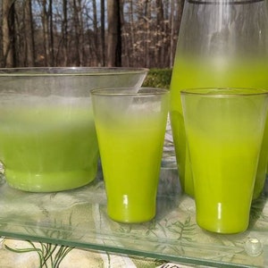 May include: A set of green glass drinkware, including a pitcher, two glasses, and a punch bowl. The glasses and pitcher have a frosted finish and a green ombre effect.