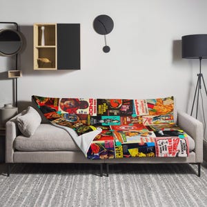 Może przedstawiać: Kolorowy koc z miękkiej, pluszowej tkaniny z kolażem vintage plakatów filmowych. Plakaty są w różnych kolorach i przedstawiają zdjęcia aktorów i aktorek. Koc idealnie nadaje się do dodania odrobiny vintage'owego stylu do każdego pomieszczenia.