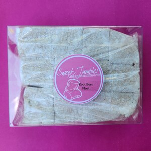 K&ouml;nnte beinhalten: Ein durchsichtiger Plastikbeh&auml;lter gef&uuml;llt mit wei&szlig;en, quadratischen Marshmallows. Der Beh&auml;lter hat ein rosa-wei&szlig;es Etikett mit der Aufschrift "Sweet Tumbles Artisan Marshmallows" und "Root Beer Float".