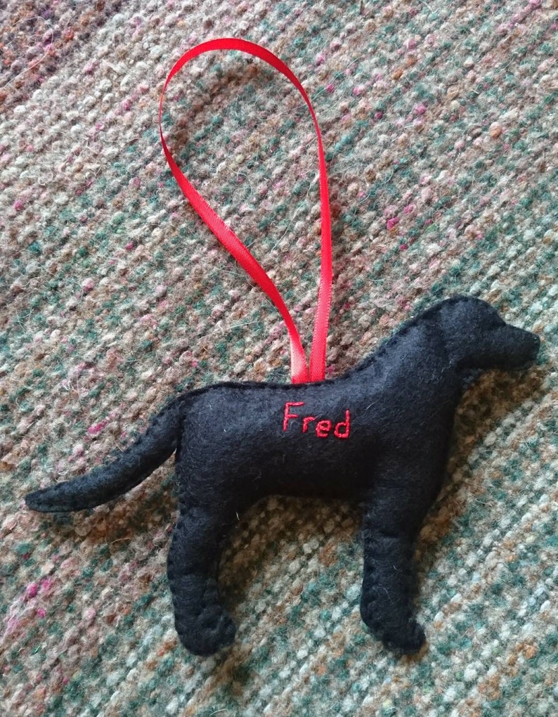 May include: Black felt dog ornament with red ribbon and the name "Fred" embroidered on the side.
