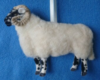 May include: A white sheep with black and white markings on its legs and face. The sheep has brown curled horns and is made of felt.