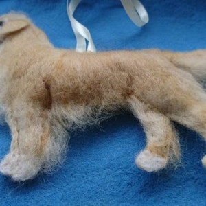 K&ouml;nnte beinhalten: Ein handgefilzter Golden Retriever Hundefiguren-Anh&auml;nger. Der Hund steht auf allen vieren mit eingerolltem Schwanz. Der Anh&auml;nger ist aus Wolle gefertigt und hat ein realistisches Aussehen.