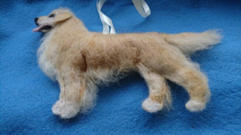 K&ouml;nnte beinhalten: Ein handgefilzter Golden Retriever Hundefiguren-Anh&auml;nger. Der Hund steht auf allen vieren mit eingerolltem Schwanz. Der Anh&auml;nger ist aus Wolle gefertigt und hat ein realistisches Aussehen.