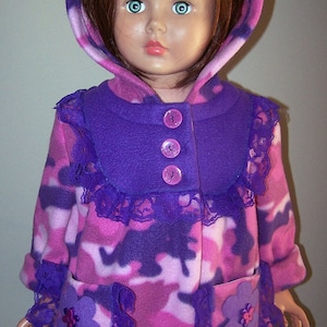 May include: A pink and purple fleece jacket with a purple hood and lace trim. The jacket has a zipper closure and buttons. The jacket has a camouflage pattern.