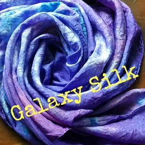 May include: A purple, blue and white tie-dye silk scarf with the text "Galaxy Silk" in yellow.