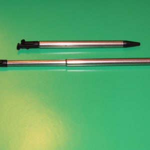 May include: Two silver stylus pens with black tips. The pens are different lengths.