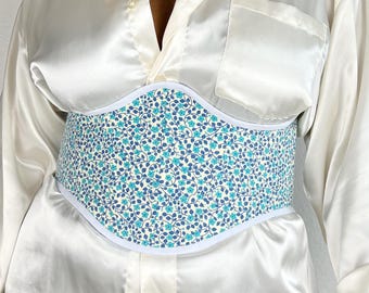 Pode incluir: Uma camisa de cetim branco com um cinto de espartilho de estampa floral azul e branco.