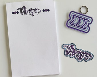May include: A white notepad with the text "Tri Sigma" written in black cursive script. There are three purple dots on each side of the text. There is a purple and blue keychain with the letters "ZZZ" in a layered design. There is also a purple and blue sticker with the text "Tri Sigma" in a layered design.
