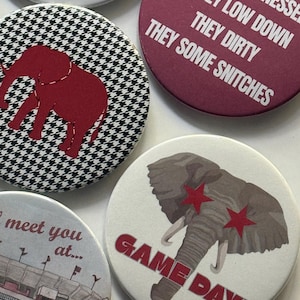 May include: A collection of round buttons with various designs and text. One button features a red elephant on a black and white houndstooth pattern. Another says "I HATE TENNESSEE THEY LOW DOWN THEY DIRTY THEY SOME SNITCHES."