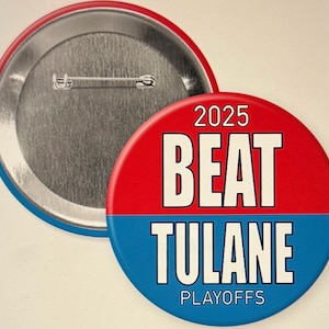 May include: A red, white, and blue button with the text "2025 BEAT TULANE PLAYOFFS." The button has a pin back and a red and blue border. The button is round.