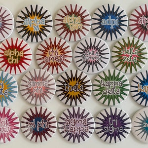 May include: Twenty round buttons with a starburst design and various sorority names, including Alpha Phi, Alpha Chi, Alpha Gamma, Adpi, Alpha Theta, Chi Omega, Delta Gamma, Delta Zeta, Tri Delta, Gamma Phi, Theta, Kappa Delta, Kappa, Phi Mu, Pi Phi, Sigma Kappa, Tri Sigma, and Zeta.