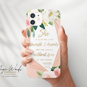 Könnte beinhalten: Eine rosa Handyhülle mit floralem Design und goldenem Text. Die Hülle zeigt die Worte "Sie ist bekleidet mit Stärke und Würde und sie lacht ohne Furcht vor der Zukunft" aus Sprüche 31:25. Die Hülle trägt auch den Text "Magic Words Premium Phone Cases".