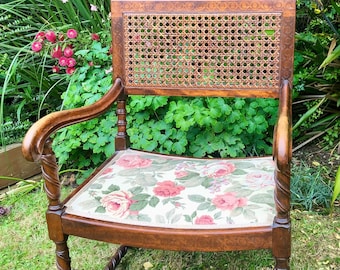 May include: A wooden chair with a cane back and a floral patterned cushion. The chair has a twisted design on the legs and arms.