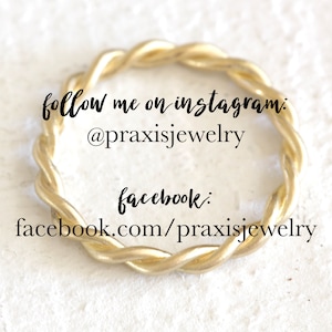 May include: A gold twisted ring with the text "follow me on instagram: @praxisjewelry facebook: facebook.com/praxisjewelry"