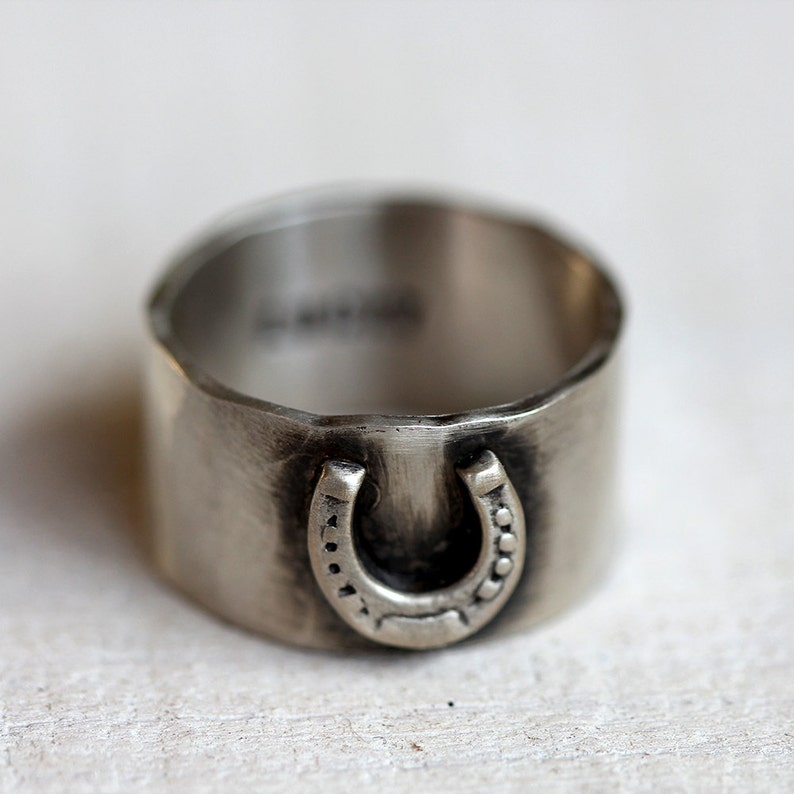 Lucky horseshoe ring. Sterling silver wide band ring with a horseshoe on the front and the word lucky engraved on the inside of the hammered band.