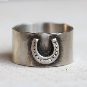 Lucky horseshoe ring. Sterling silver wide band ring with a horseshoe on the front and the word lucky engraved on the inside of the hammered band.