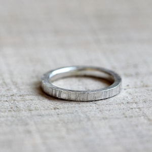 May include: A silver band ring with a textured, hammered finish.