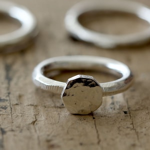 May include: A silver ring with a hammered, octagonal-shaped band and a textured, octagonal-shaped top.