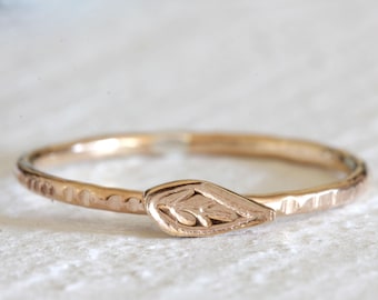 Puede incluir: Un delicado anillo de oro rosa con una banda martillada y un diseño de hoja. La hoja está centrada en la banda y tiene un patrón grabado detallado.